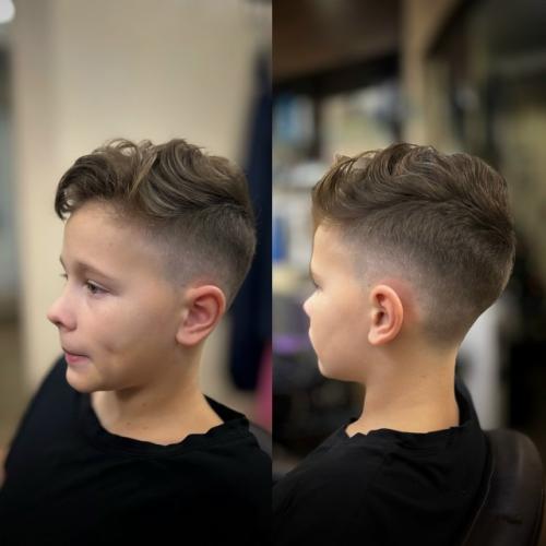На фото представлена современная модельная стрижка для мальчика, сочетающая элементы фейда и текстурированного верха. 

